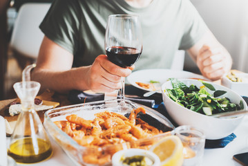 Hipster guy toasting with glasses of red wine while celebrating anniversary at cozy atmosphere, holidays and enjoyment concept