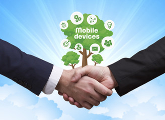 Technology, the Internet, business and network concept. Businessmen shake hands: Mobile devices