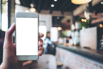 Mockup image of a hand holding white mobile phone with blank white screen in vintage cafe