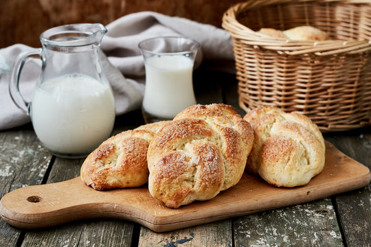 Homemade sweet braided yeast bread on a wooden cutting board and a jug of milk.horizontal