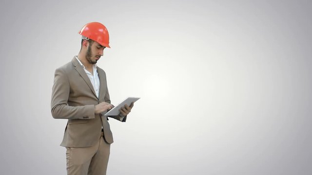Engineer in safety helmet conducting inspection with tablet on white background.