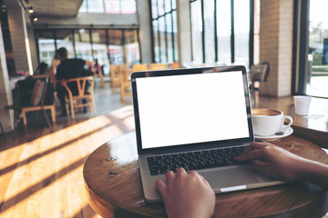 Mockup image of a woman using laptop with blank white screen on wooden table in modern loft cafe - obrazy, fototapety, plakaty