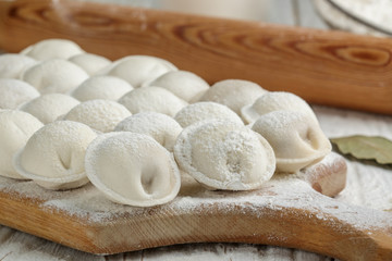 Fototapeta na wymiar Process of making homemade raw dumplings with meat filling on a wooden Board. Pelmeni. A traditional dish of Russian cuisine. Selective focus 