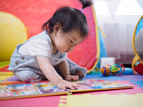 baby girl reading book at home