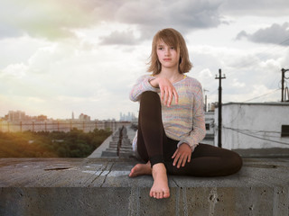 Teenage girl sitting high on the roof. The city, the sun's rays