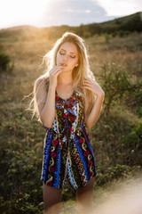 Naklejka premium Beautiful blonde with beautiful eyes in blue overalls in nature, sunset sun