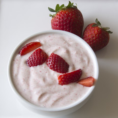 Greek strawberry yoghurt served with delicious strawberries in a bowl