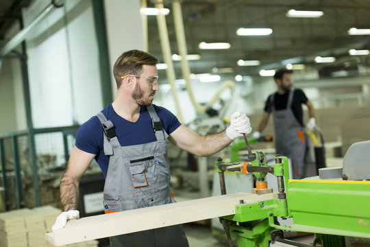 Young man works in a factory for the production of furniture