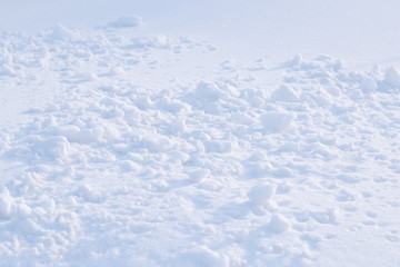 Fototapeta na wymiar Snowballs on snowy surface. Background. Snow clods of different sizes are scattered on a flat snow surface.