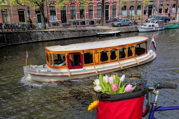 Poster Famous Amsterdam with basket of colorful tulips against boat in Holland © Tomas Marek
