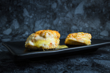 Chicken breast spicy with cheese in dark background.