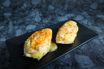 Chicken breast spicy with cheese in dark background.
