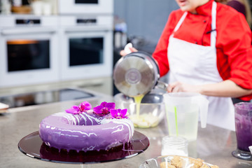 The confectioner prepares a gentle  purple lilac violet mass cake with orchids