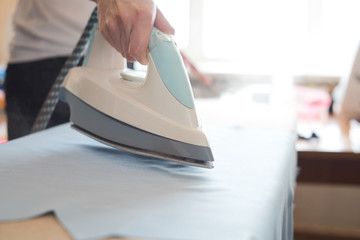 Woman tailor ironing textile with steaming on the iron board before starting work