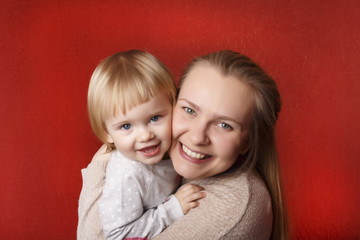 Crazy mother with tiny little blond doughter. Red background. Copy Space.