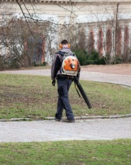 man in the park with hand leaves blower cleaning the walkwayan with leaves blower