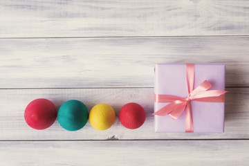 Obraz premium Gift box with painted eggs over wooden background