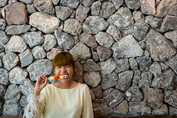 Obraz na płótnie Canvas Happy lady eating fresh fruit ,standing over stone wall background