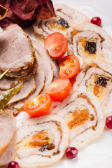 Meat plate with delicious pieces of sliced ham, cherry tomatoes, herbs and meat with cranberry. Close up with selective focus