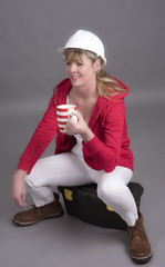 Woman worker wearing a hard hatand holding a mug