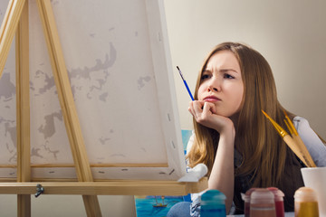 Blonde is bored during training. Student of art school. A woman paints a painting on canvas.