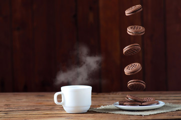 Cookies in flight and a cup of hot tea, close-up on a wooden table.