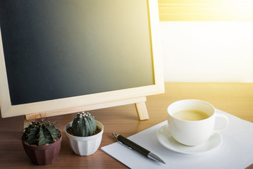 cup of coffee and wooden blackboard with sunset