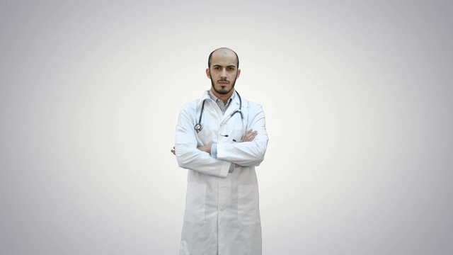 Serious medical worker standing with his arms across his chest on white background.