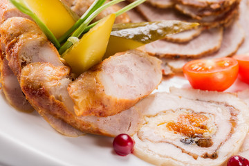 Meat plate with delicious pieces of sliced ham, cherry tomatoes, herbs, cucumber and meat with cranberry. Close up with selective focus