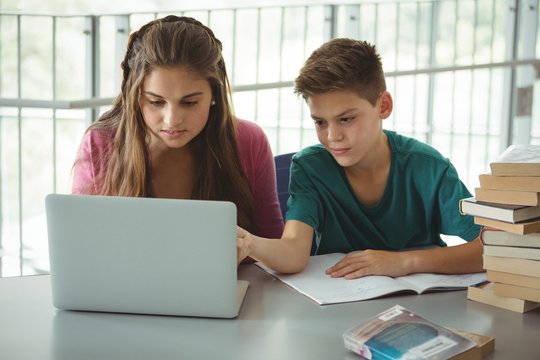 School kids using laptop in library