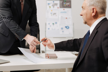 Doubtful aged businessman signing the contract in the office