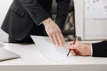Confident businessman signing the important document in the office