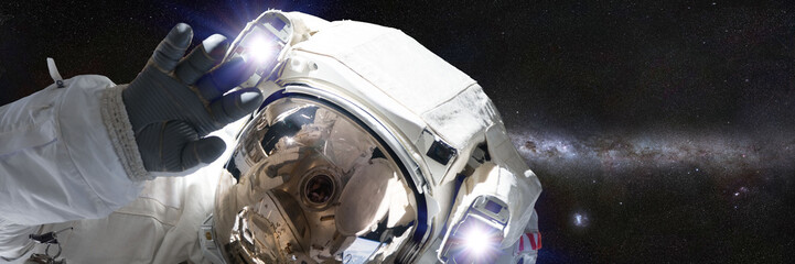 astronaut in front of the Milky Way galaxy waving at camera (banner format 3x1, elements of this image are furnished by NASA)