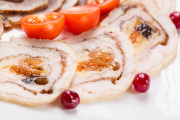 Meat rolls with cherry tomatoes and cranberry on white plate. Close up with selective focus