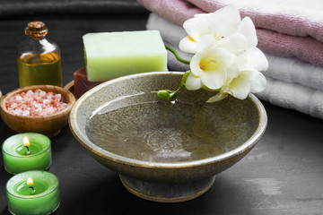 Relaxing spa setting with water bowl and flowers, candles, oil, natural soap, salt and towels.Wellness set