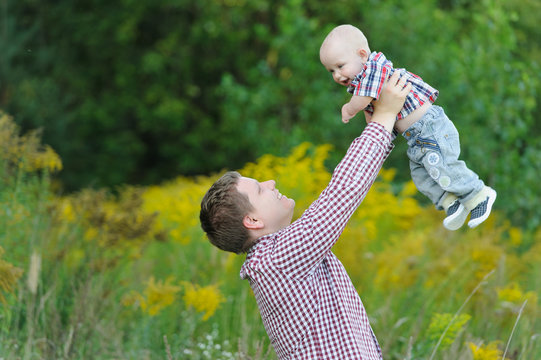 Happy Young Father Lifting Up His Son