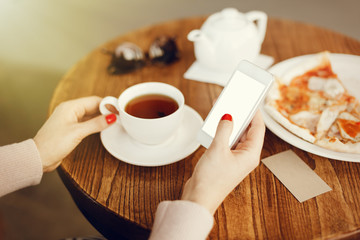 Girl holding smartphone with empty screen at cafe