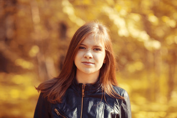 Young adult girl portrait in autumn park yellow leaves background