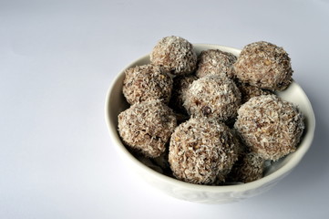 Homemade cookies - millet flake balls in grated coconut in white bowl
