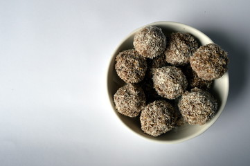 Homemade cookies - millet flake balls in grated coconut in white bowl