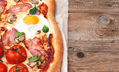 Fresh delicious pizza from the oven with egg, prosciutto and tomato