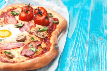 Fresh delicious pizza from the oven with egg, prosciutto and tomato