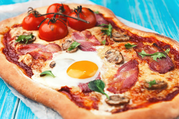 Fresh delicious pizza from the oven with egg, prosciutto and tomato
