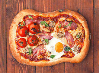 Fresh delicious pizza from the oven with egg, prosciutto and tomato