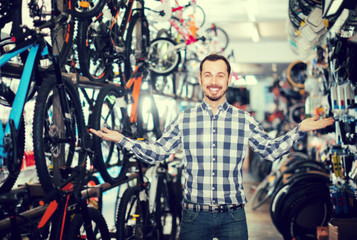 Plakat interested man in bicycle shop chooses for himself sports bike