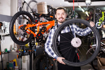 Fototapeta na wymiar man in apron considering composition of wheel for bicycle