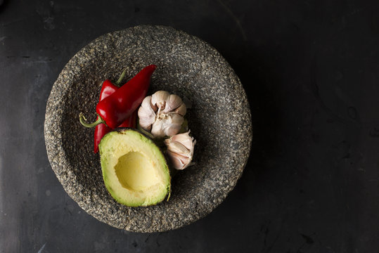 Still life of avocado, garlic and chillies in bowl, overhead view
