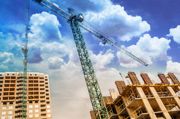 Construction crane above buildings under the clouds