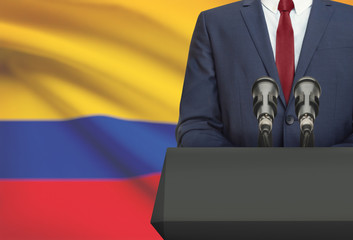 Businessman or politician making speech from behind a pulpit with national flag on background - Colombia