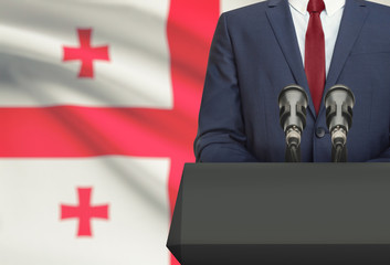 Businessman or politician making speech from behind a pulpit with national flag on background - Georgia